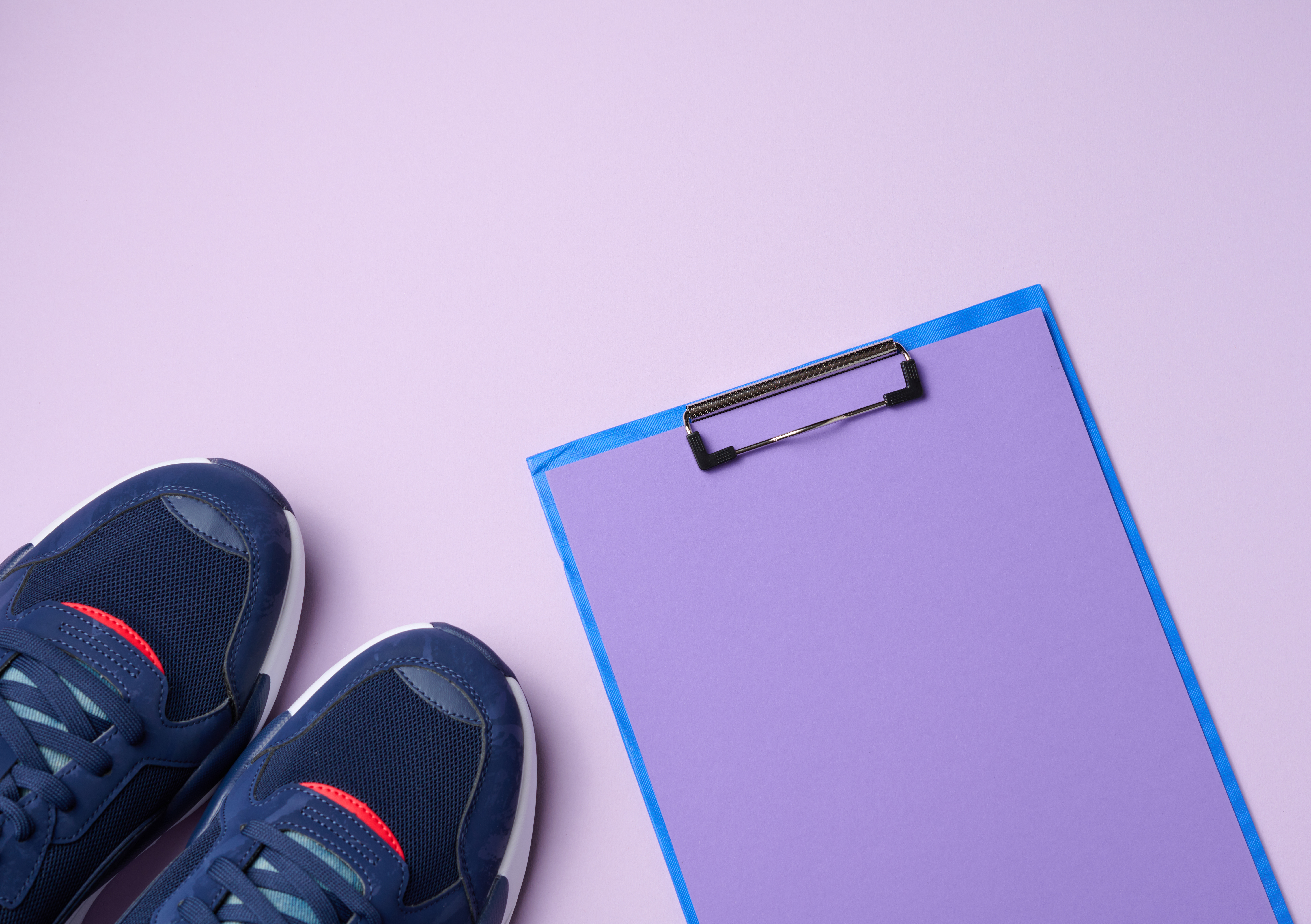 Pair of blue textile sneakers on a purple background, top view